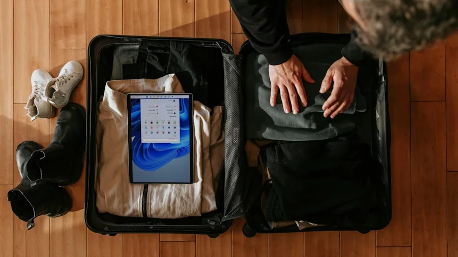 Person organizing travel essentials and documents into a laptop bag for a trip