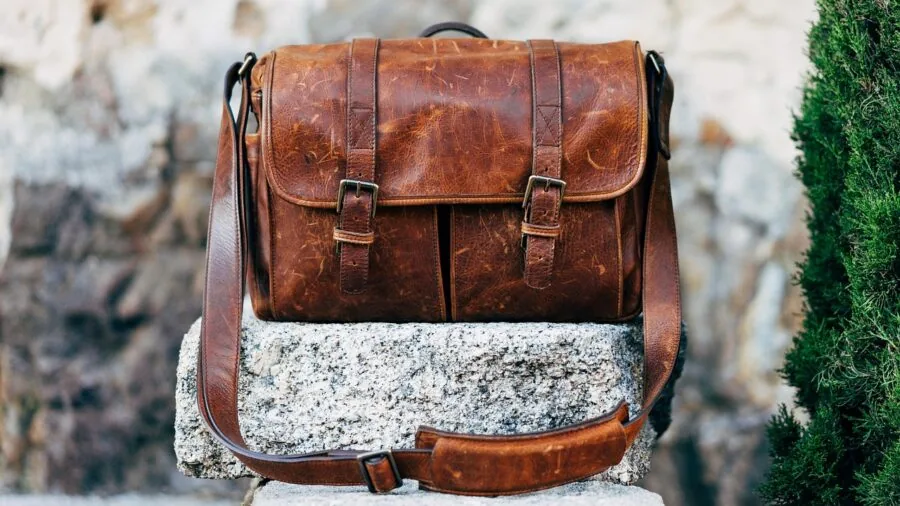 Person packing and organizing a messenger bag with laptop and daily essentials