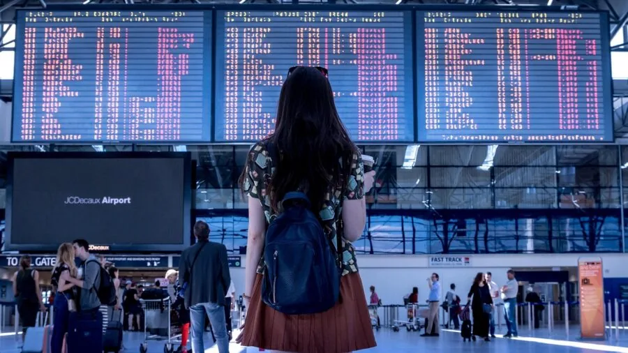 Person packing checked luggage with travel documents and security lock before airport departure