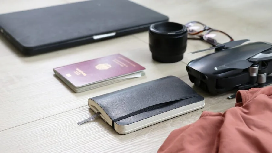 Person packing compact electronics and gear into a travel bag for a trip