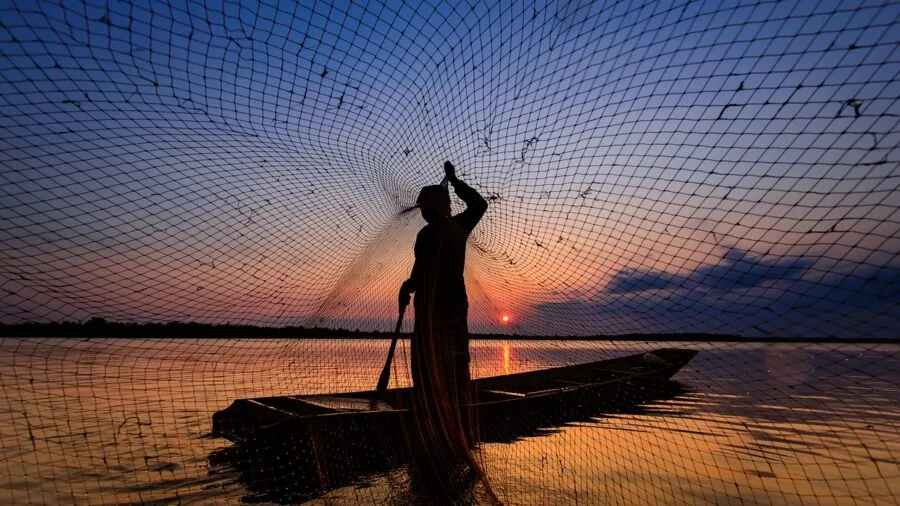 Person paddling in kayak on calm water during outdoor fishing activity