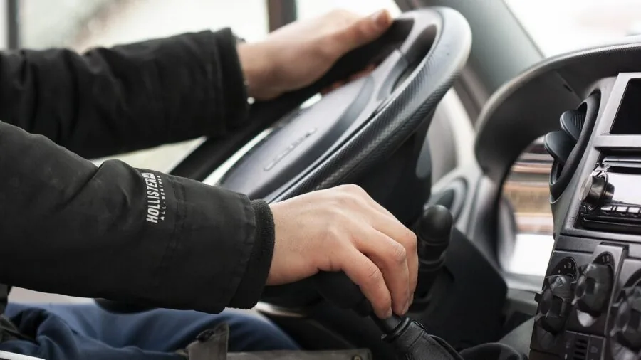 Person pairing smartphone via Bluetooth while sitting in car driver's seat