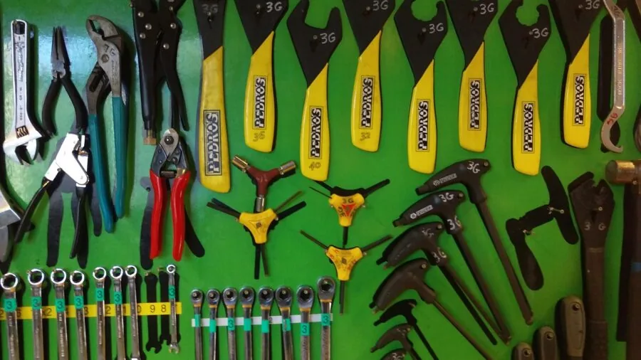 Person performing bike maintenance in a home garage workshop with various tools and equipment