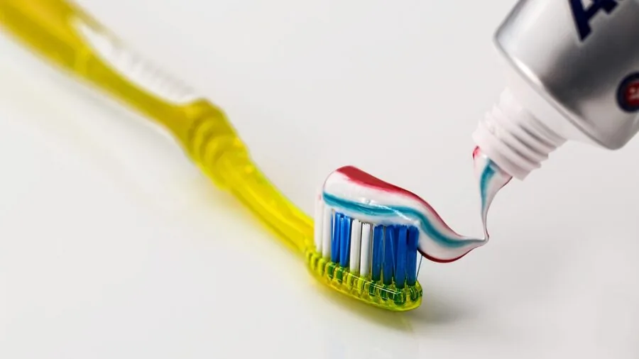 Person performing daily oral hygiene routine at bathroom sink with natural morning light