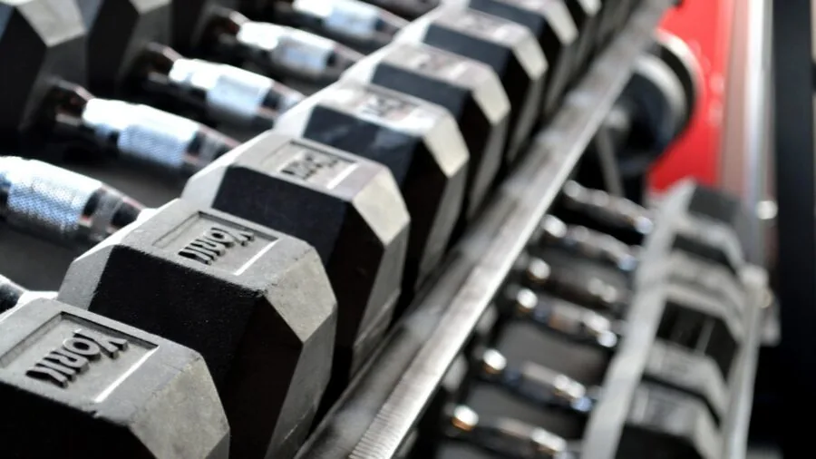 Person performing heavy barbell lift in gym setting with focused intensity