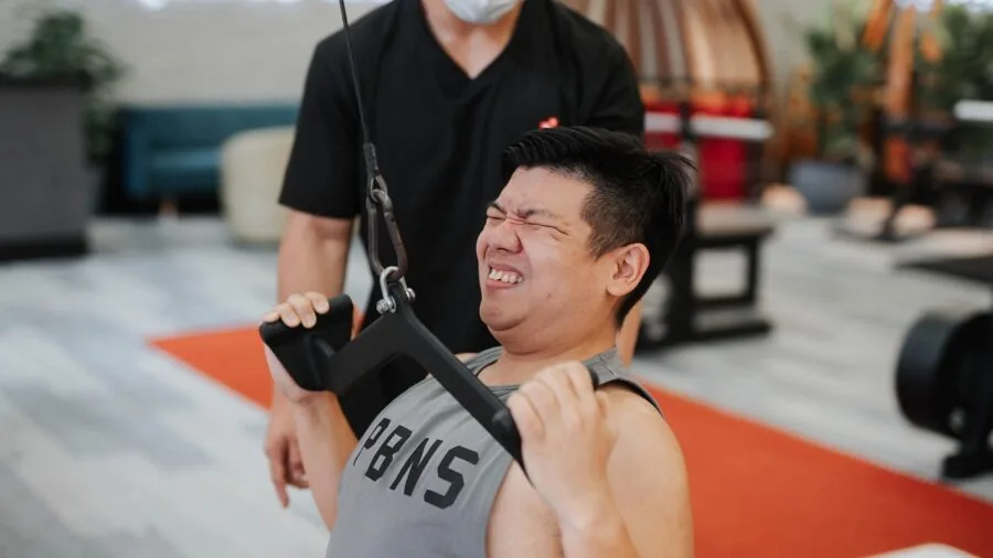 Person performing intense workout exercise with focused determination and proper form on fitness equipment