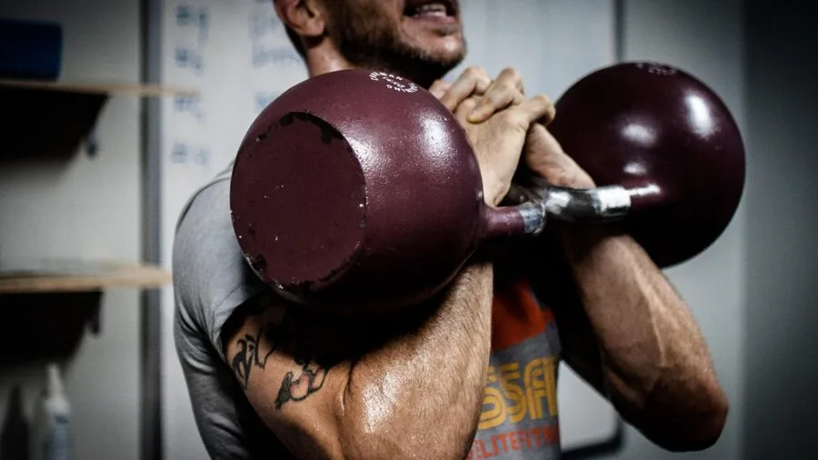 Person performing kettlebell exercise with intense concentration on proper form and control