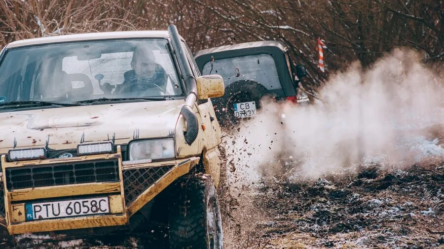 Person performing mechanical maintenance on off-road vehicle in outdoor setting