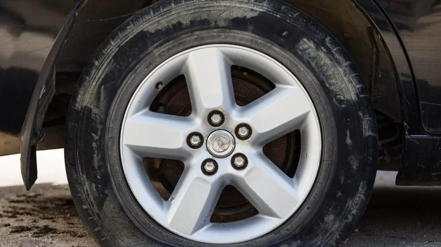 Person performing tire repair maintenance on vehicle in outdoor setting