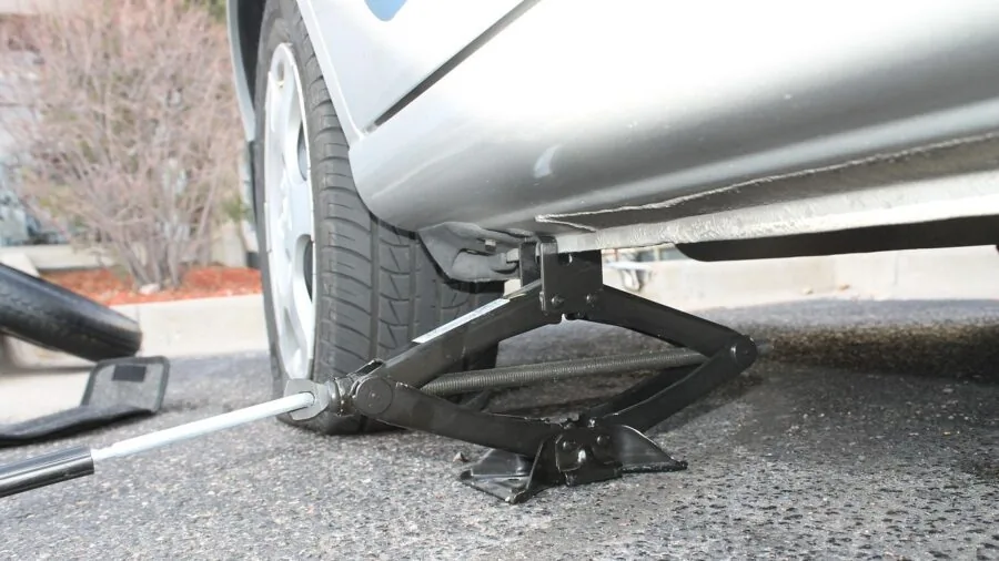 Person performing tire repair on vehicle during roadside emergency maintenance