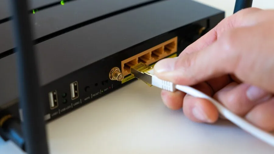 Person plugging HDMI and audio cables into back of television in home entertainment room