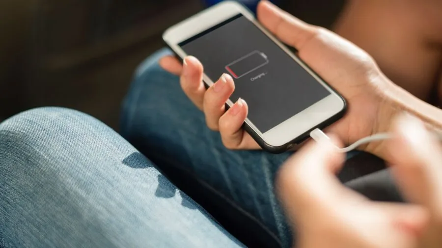 Person plugging in a portable battery charger to power device during travel or outdoor activity