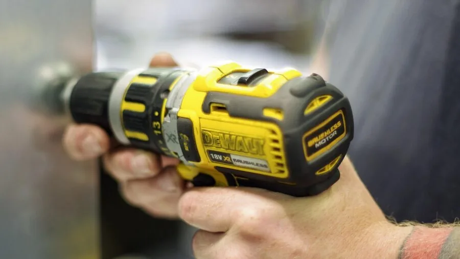 Person plugging in cordless cleaning device to wall outlet for battery charging