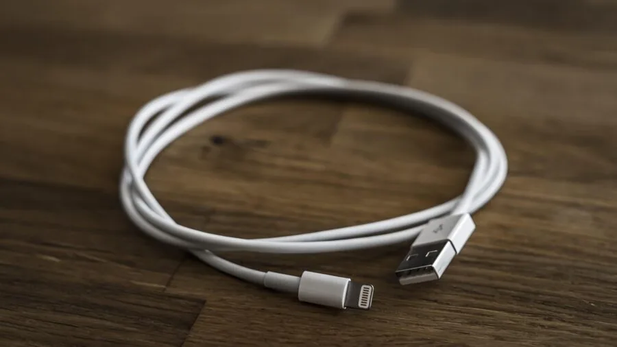 Person plugging USB cable into computer tower on desk for data transfer and device charging