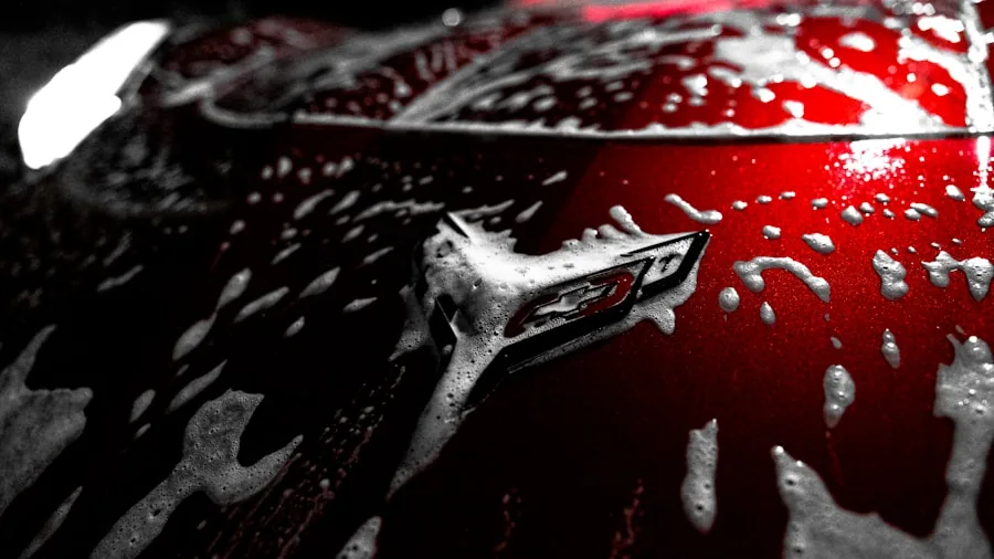 Person polishing dark car exterior with microfiber cloth for glossy finish