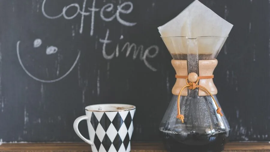 Person pouring fresh coffee into mug in bright kitchen during morning routine