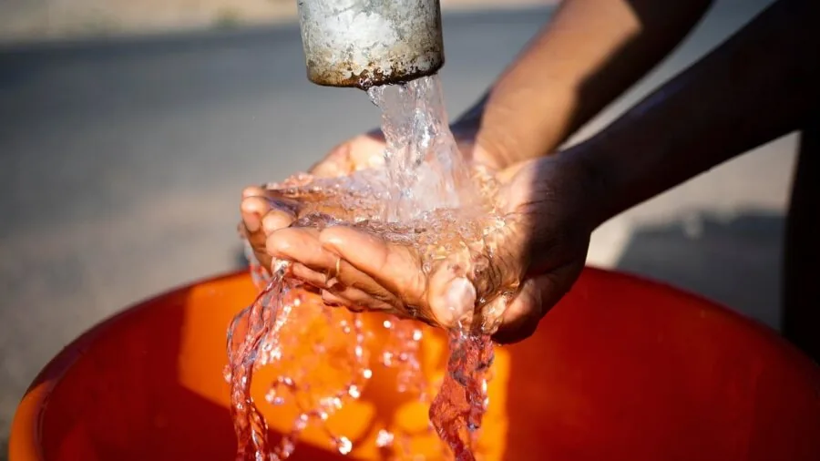 Person pouring fresh filtered water into a glass, representing safe drinking water standards and quality