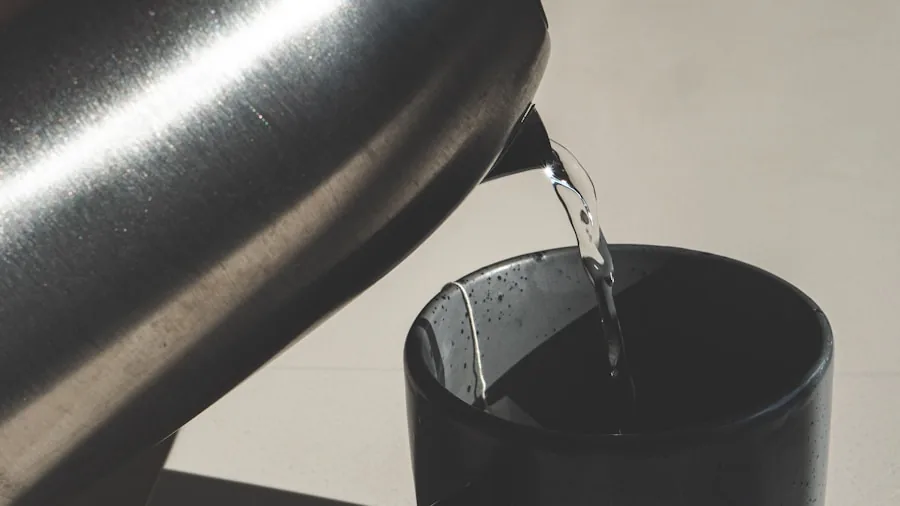 Person pouring hot water from a gooseneck kettle into a cup during morning tea preparation