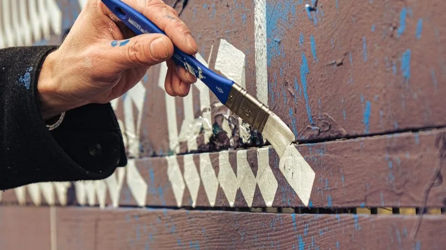Person practicing calligraphy with pen and ink at a wooden desk near natural light