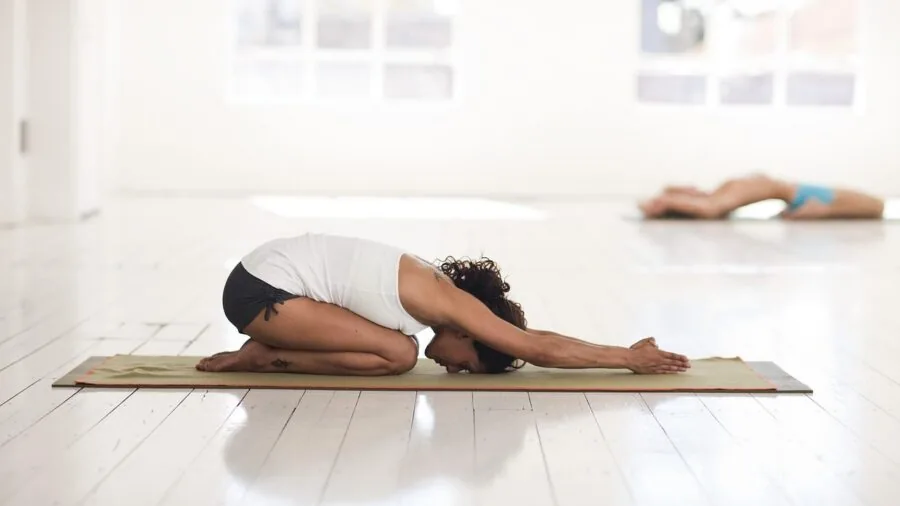 Person practicing yoga on cork mat with alignment markings during indoor fitness session