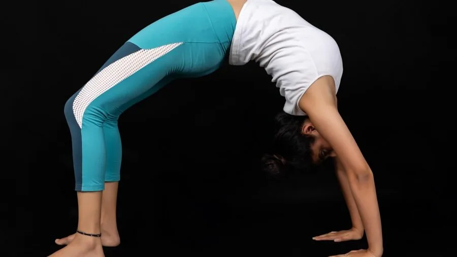 Person practicing yoga stretching exercises on a mat indoors during a wellness routine