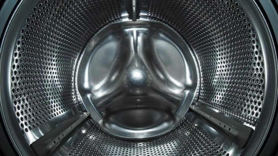 Person pulling damp laundry from front load washer after spin cycle
