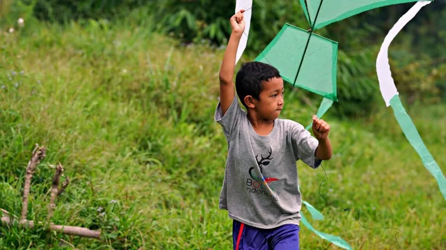 Person quickly assembling a kite on a beach or grassy field for easy setup and portability