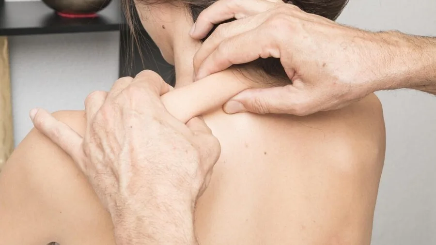 Person receiving deep tissue massage therapy on shoulder and neck muscles during wellness session