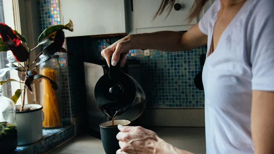 Person refilling espresso machine water tank in home kitchen during morning coffee preparation