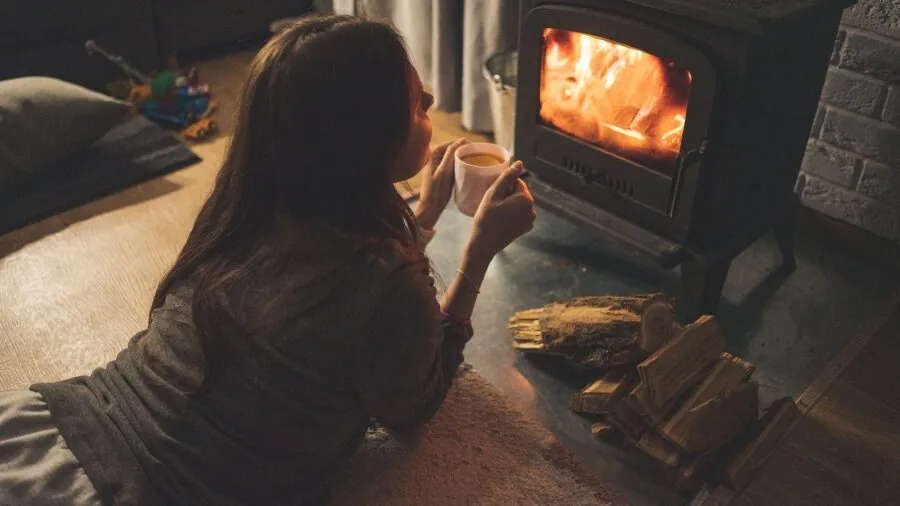 Person relaxing by cozy fireplace warming cold feet after winter sports activity