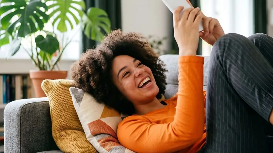 Person relaxing in comfortable chair while charging smartphone, modern home relaxation setup