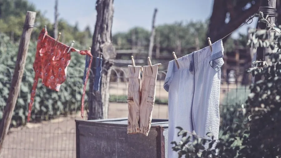 Person removing clean white linens from washing machine, demonstrating fabric care and laundry maintenance