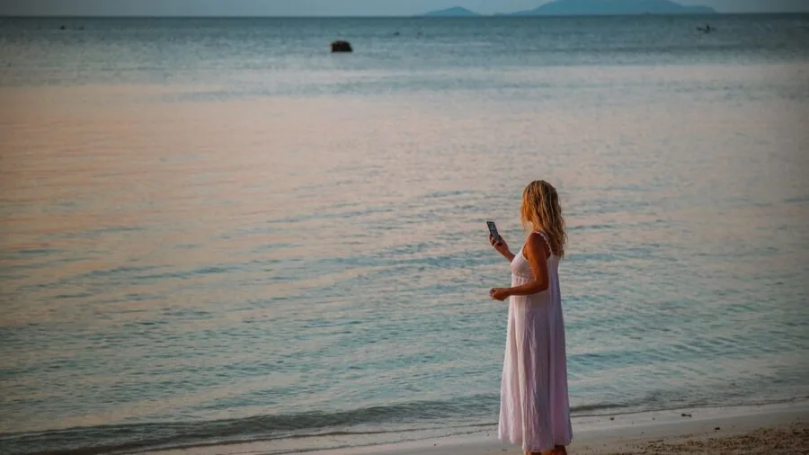 Person reviewing and sharing travel photos on smartphone in natural setting