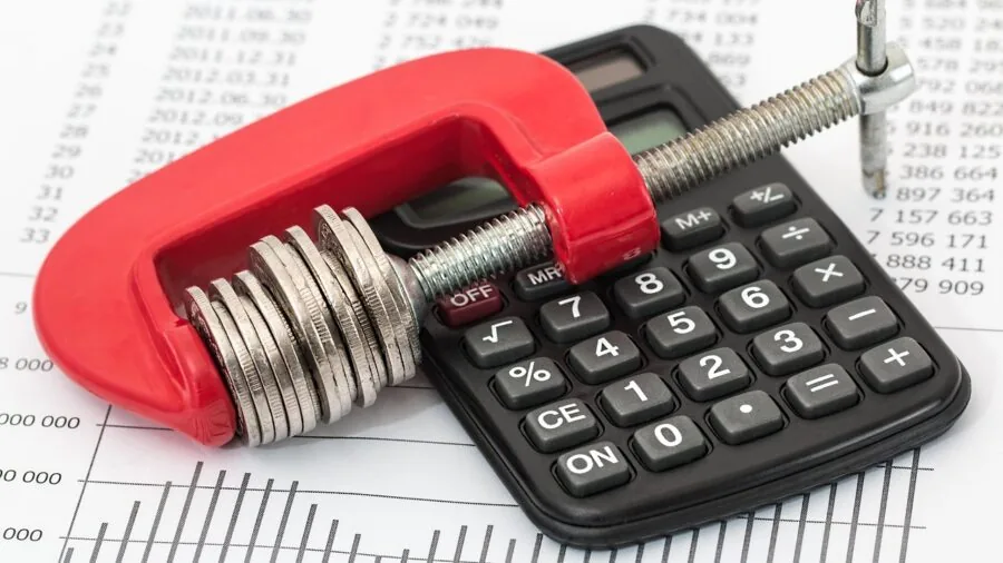 Person reviewing project costs and budget calculations at desk with calculator and notebook