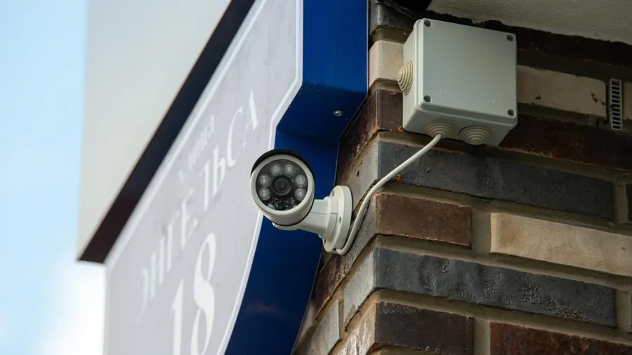 Person reviewing security camera footage on monitor in home office at night