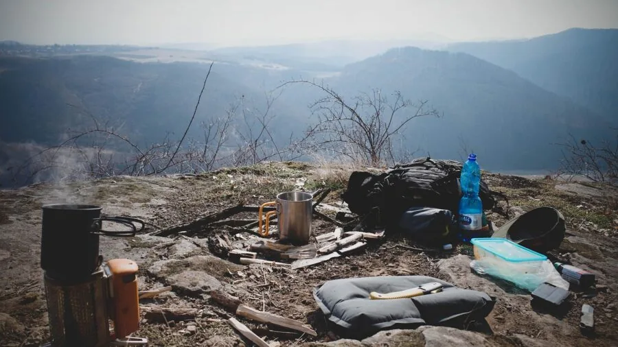 Person rinsing camping equipment in natural water source during backcountry adventure