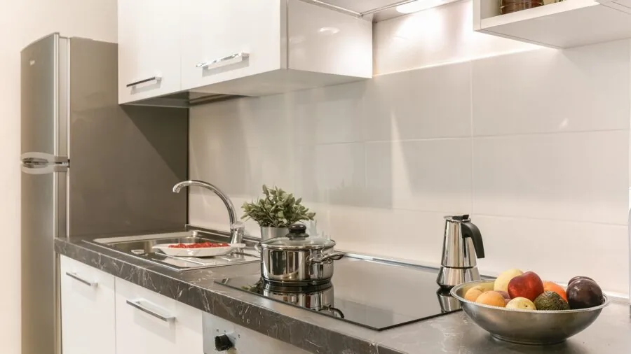 Person rinsing dishes in kitchen sink with focus on water drainage and sustainable home practices