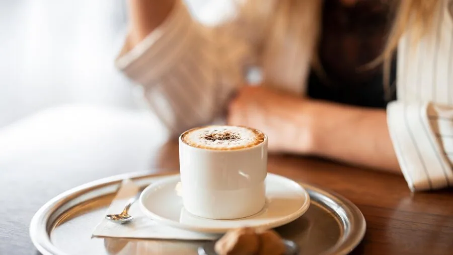 Person safely holding a warm drink while driving in a car, demonstrating secure beverage handling during travel.