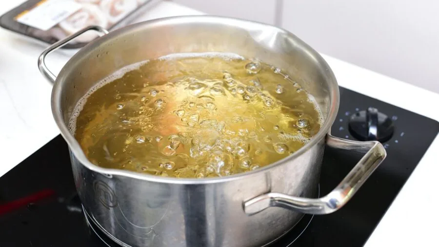 Person sautéing vegetables in a hot skillet on stovetop during meal preparation