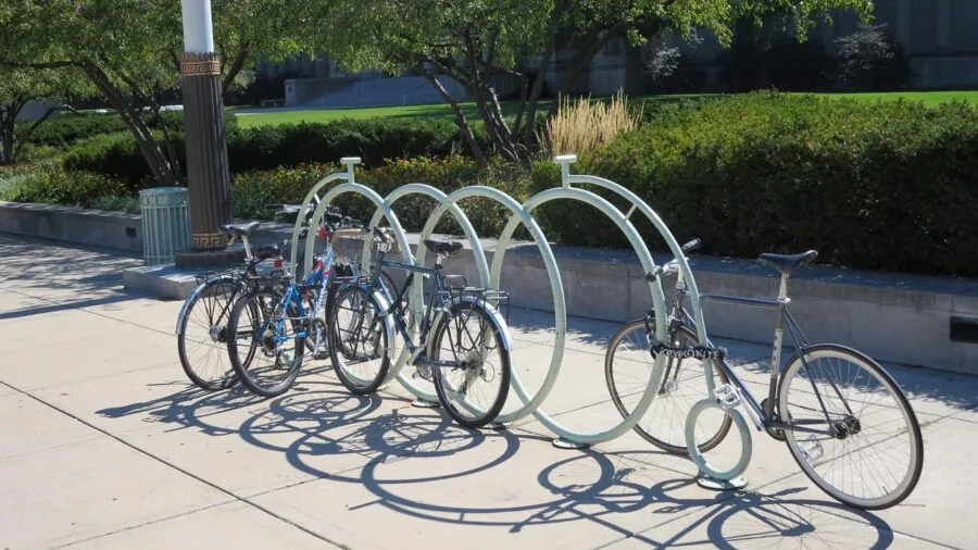 Person securing bike with cable lock to outdoor rack in urban setting