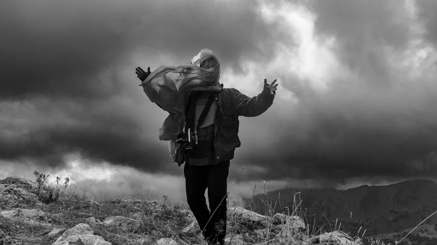 Person securing outdoor gear on ground during windy weather in natural landscape