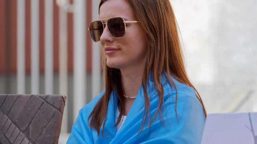 Person selecting sunglasses while shopping outdoors in natural sunlight