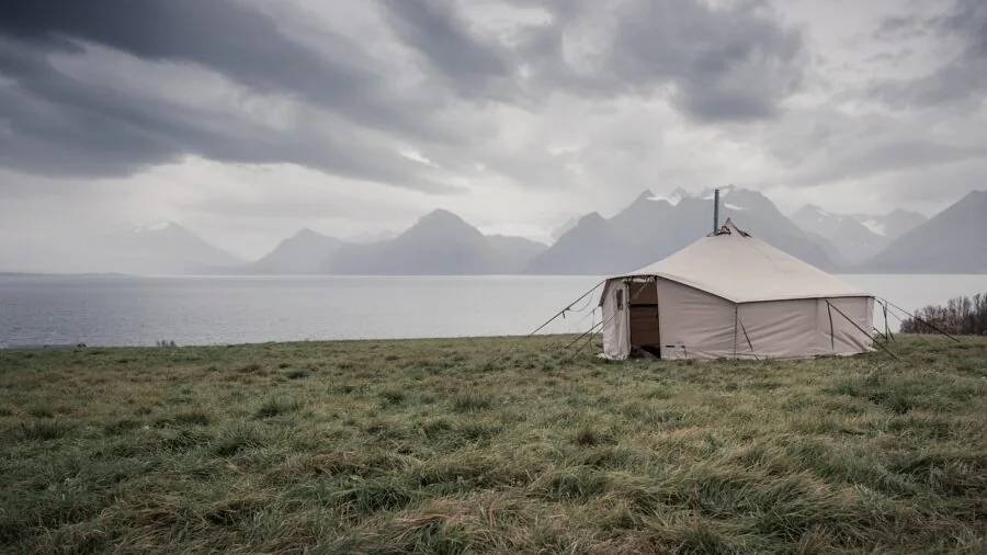Person setting up camping equipment and power system outside tent in natural campsite environment