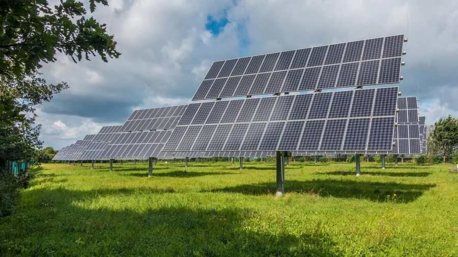 Person setting up foldable solar panels at an outdoor campsite with natural sunlight