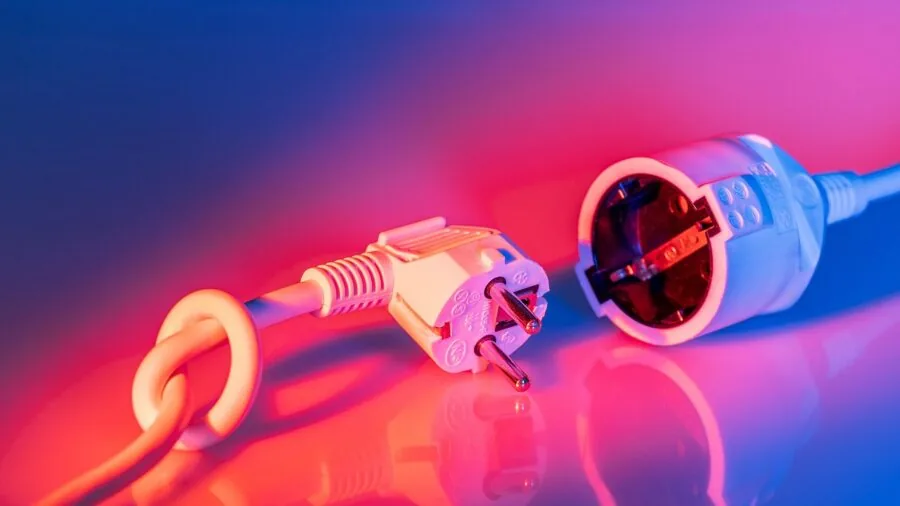 Person setting up party lights by plugging in electrical cord to wall outlet for event