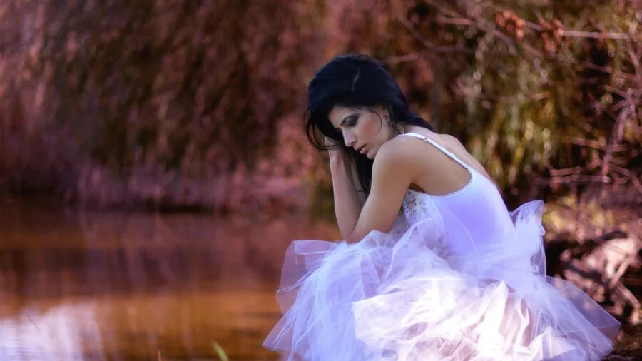 Person sitting by natural water source, watching and waiting, representing water treatment process timing
