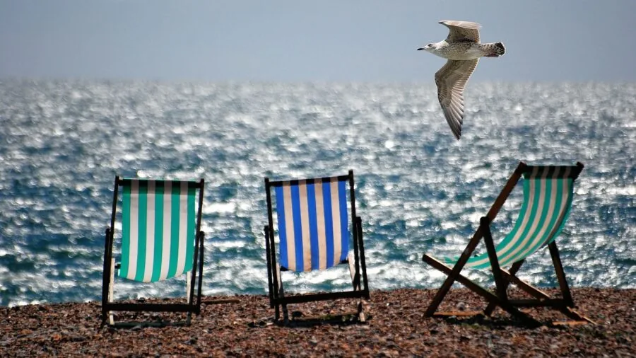 Person sitting in a beach chair enjoying the seaside, showing fabric and comfort details in natural daylight