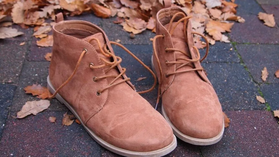 Person sitting indoors warming their feet and boots by a heat source during cold weather