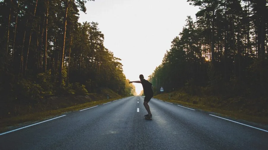 Person skateboarding on a longboard down a smooth paved street in natural daylight