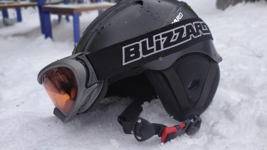 Person skiing down mountain slope wearing protective helmet in winter conditions